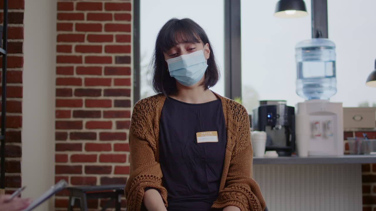 Sad woman crying at aa therapy meeting in front of group of people during covid 19 pandemic