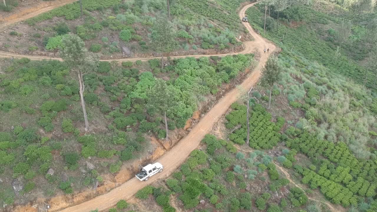 Aerial Over White Truck Going Through Tea Plantation In Sri Lanka. Follow Shot