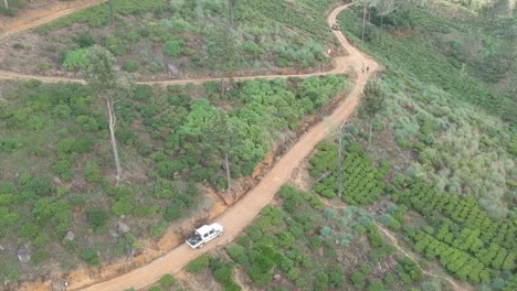aerial over white truck going through tea plantation in sri lanka. follow shot