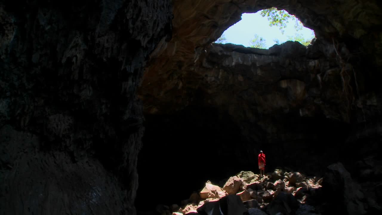 un guerrero masai se baña en un charco de luz en una cueva en kenia