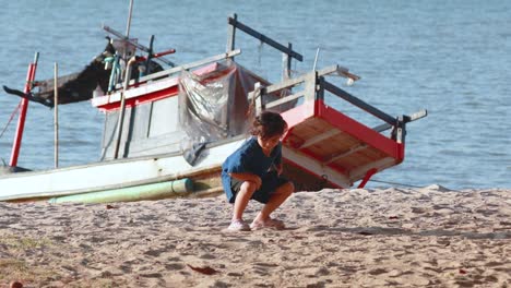 a child explores the sandy beach near boats