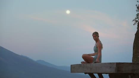 woman on wooden platform grabbing notebook to write down feelings during full moon