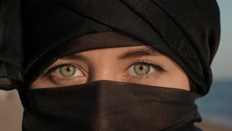 young woman in hijab open her green eyes and looking at camera portrait close up