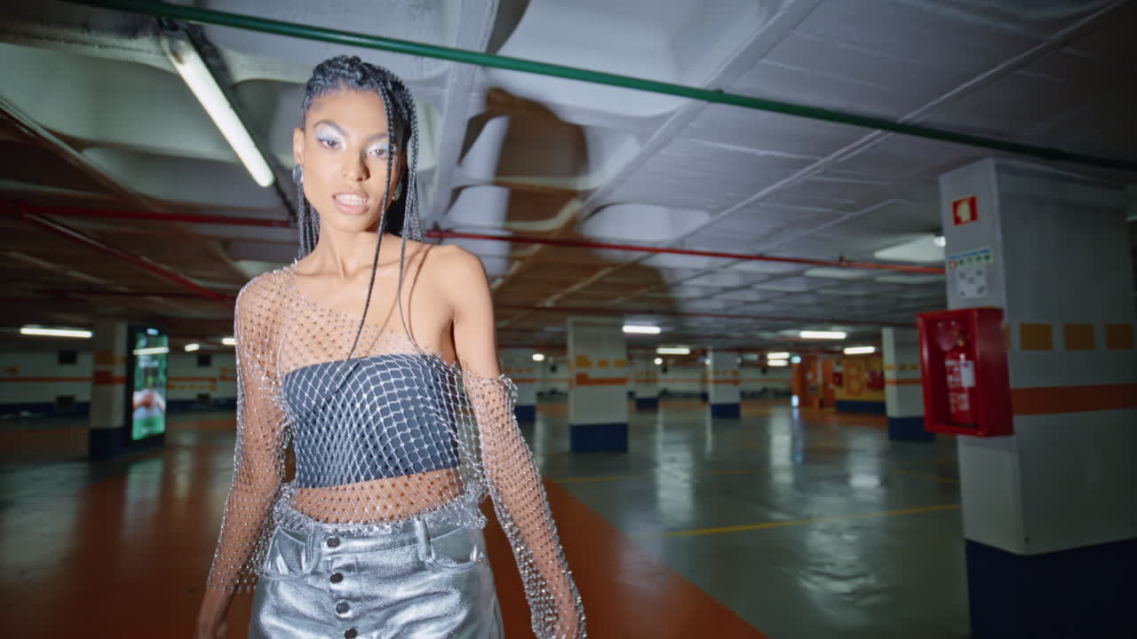 feliz morena fashionista buscando cámara paseando por las columnas de la noche retrato