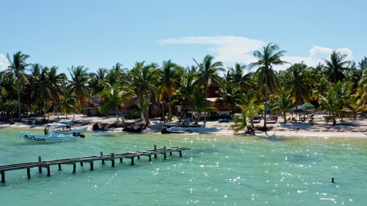 toma aérea de la costa de un pequeño pueblo pesquero en la reserva natural de sian ka'an cerca de tulum, méxico con pequeños barcos de pesca, muelles, palmeras y arena blanca en un día de verano