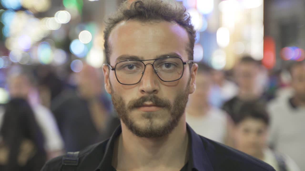 Giovane che cammina tra la folla guardando la fotocamera