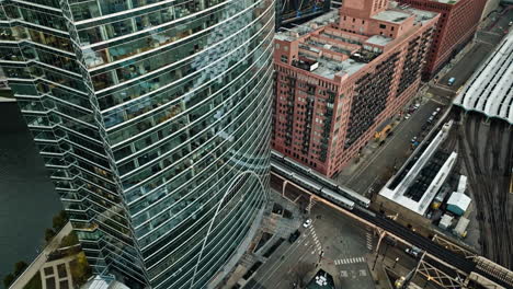 Drone-shot-of-a-trains-in-front-of-a-skyscraper-and-a-railway-station-in-Chicago