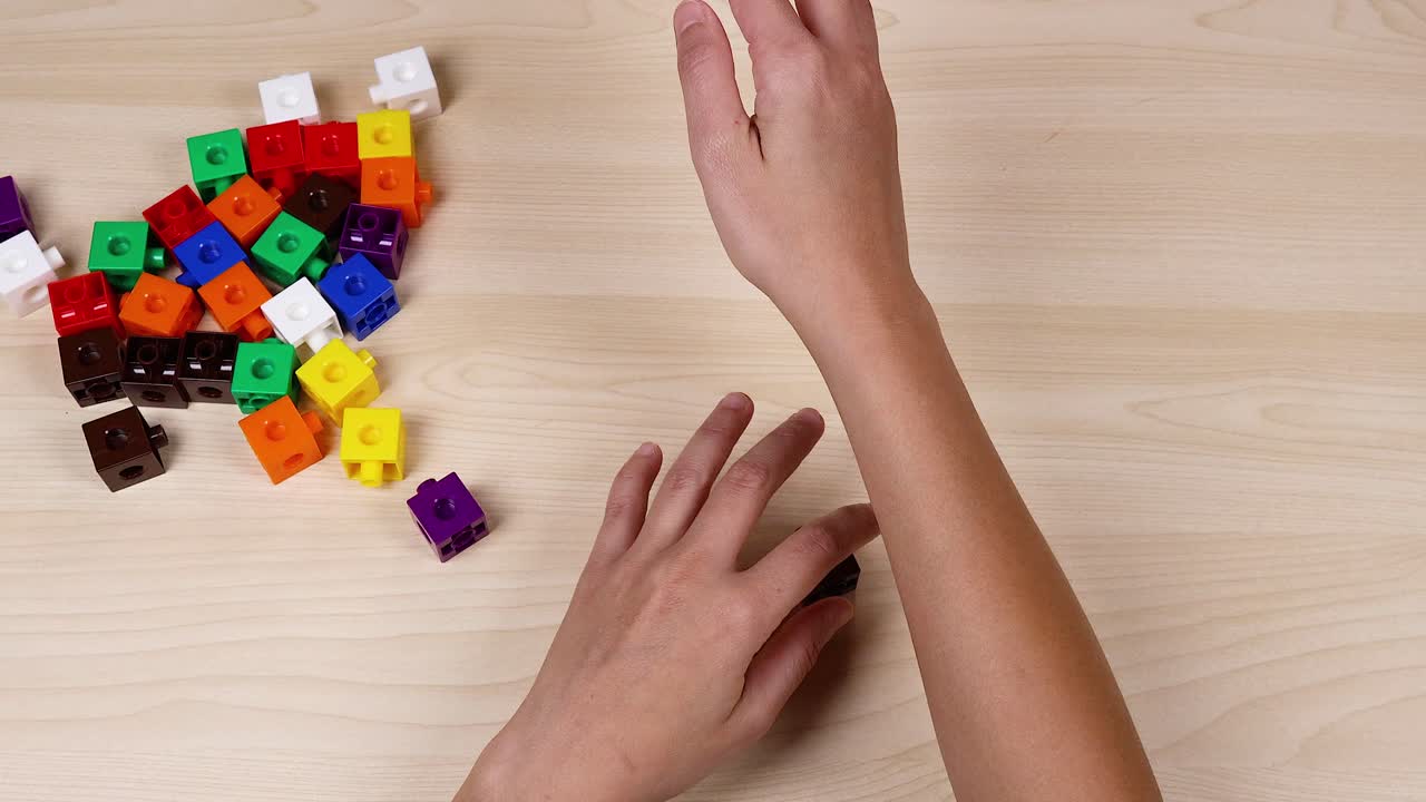 las manos organizan cubos coloridos en una mesa