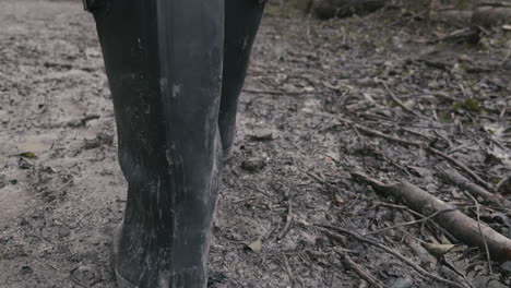 Muddy-boots-walking-down-a-muddy-path,-rear-view,-slow-motion