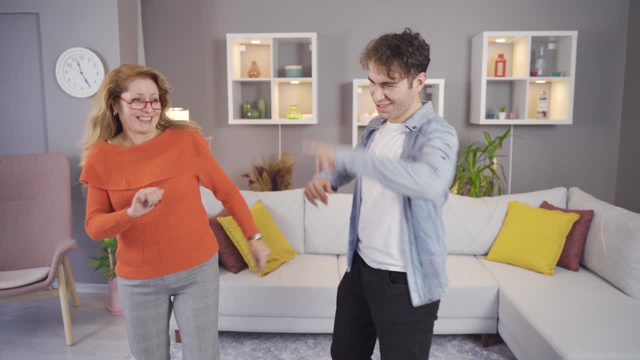 Mother and son are dancing happily at home.