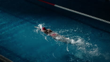 una mujer nadando en una competencia en una piscina cubierta