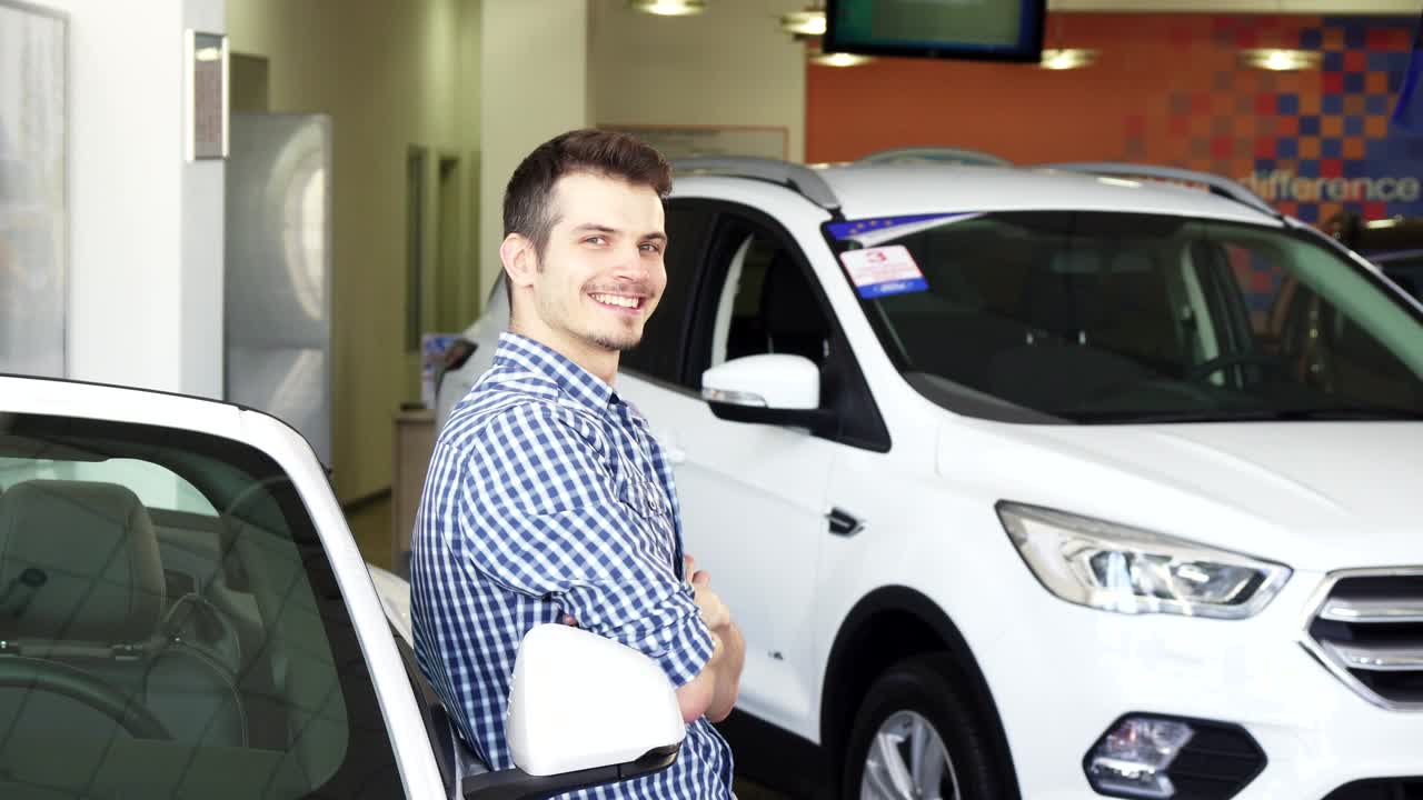 feliz joven apuesto posando con su nuevo coche mostrando las llaves