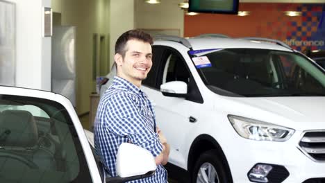 feliz joven apuesto posando con su nuevo coche mostrando las llaves