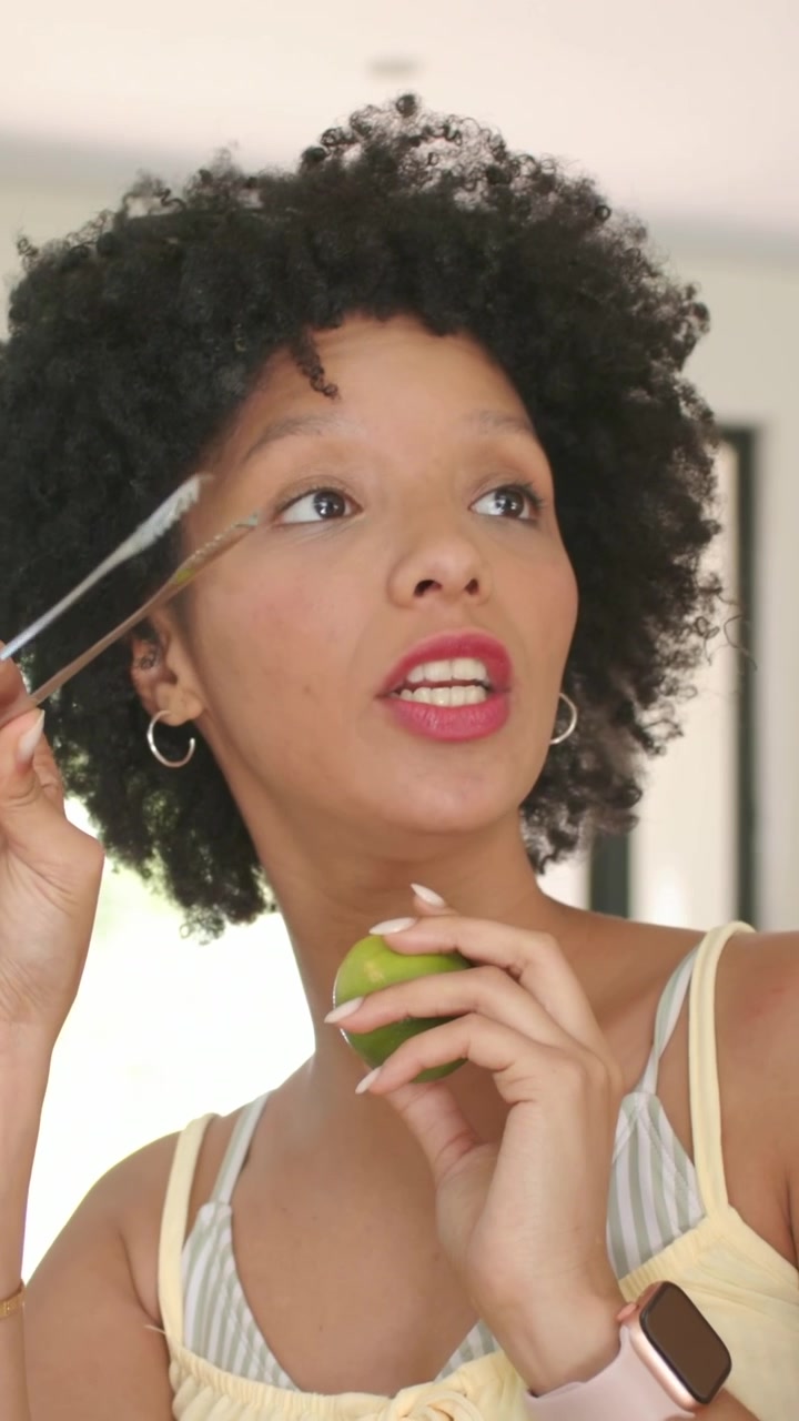 Vertical video: Camera panning woman in yellow holding lime and tongs at counter prepping citrus