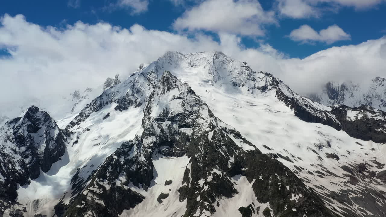 눈 덮인 아름다운 산봉우리와 빙하 위로 산 구름을 통과하는 항공 비행.