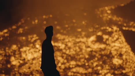 pacaya volcano, guatemala - a silhouette of a man with a headlamp stands near the rivers of molten lava at night - handheld shot