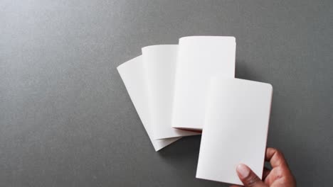 mano sosteniendo un pedazo de papel sobre pedazos de papel con espacio de copia en fondo gris en cámara lenta