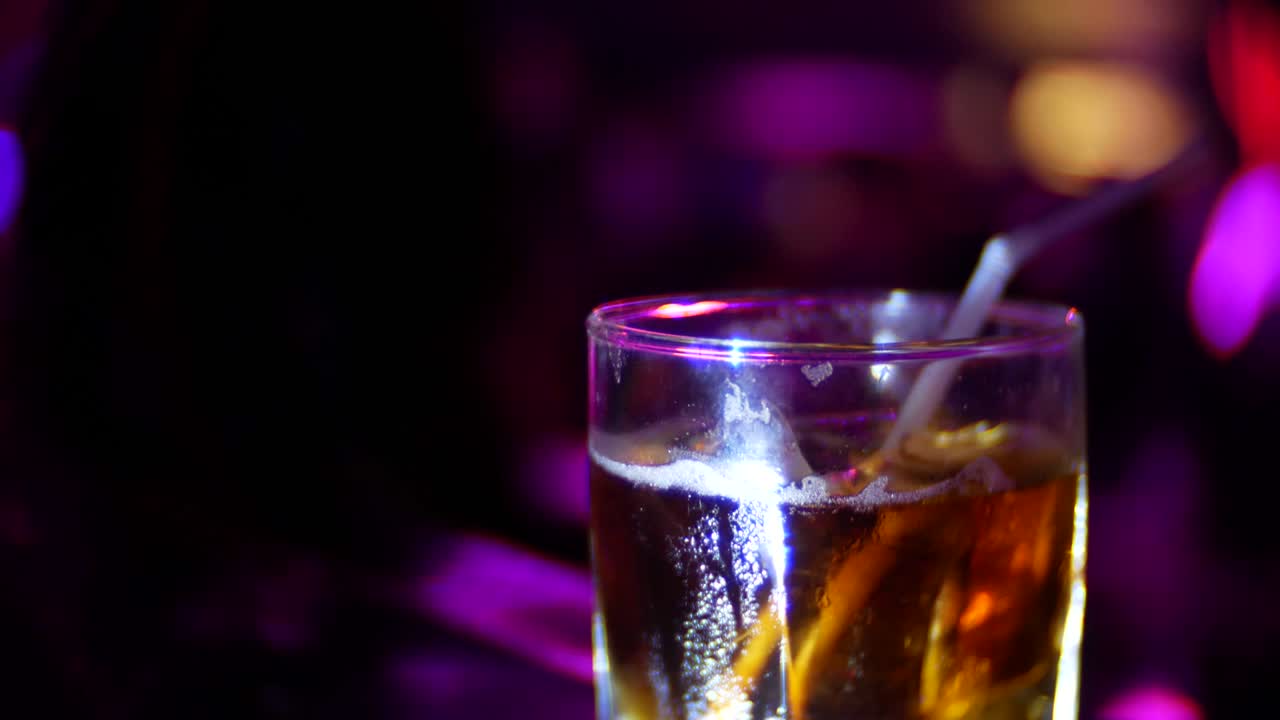 primo piano di un cocktail alcolico in bicchiere sul bancone di un bar, in un nightclub. sfocamento dello sfondo, 4k