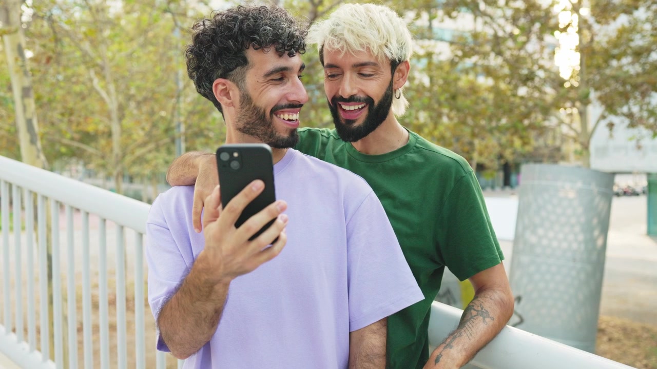 Dois homens felizes rindo enquanto olham para um smartphone ao ar livre