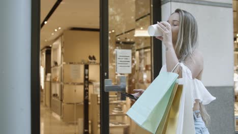 mujer rubia caminando por la calle y escribiendo en el teléfono inteligente