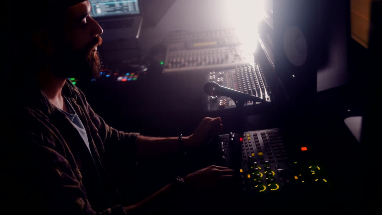 Ung hipster-DJ arbejder på lydmixer og producerer musik.
