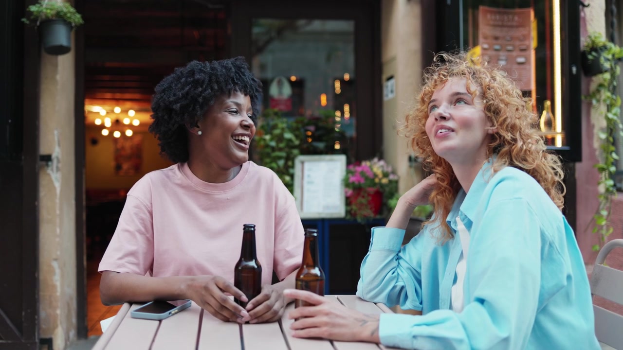 Two Happy Women Talking and Laughing at an Outdoor Cafe