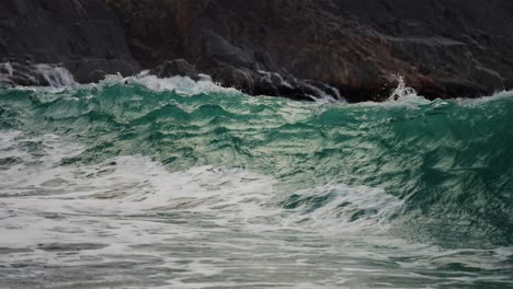 poderosas olas ruedan sobre las rocas y se derraman en la playa de arena