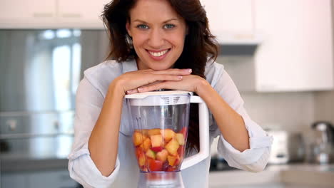 Pretty-brunette-leaning-on-blender-smiling-at-camera