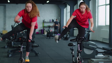 Group-of-girls-performs-aerobic-training-workout-cardio-routine-on-bike-simulators,-cycle-training