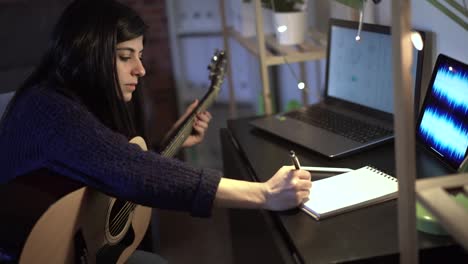 musician playing guitar in room and taking notes