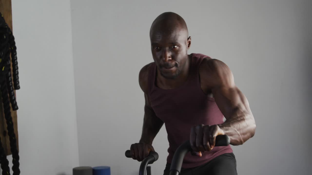 Fit african american man exercising on training bike inside gym