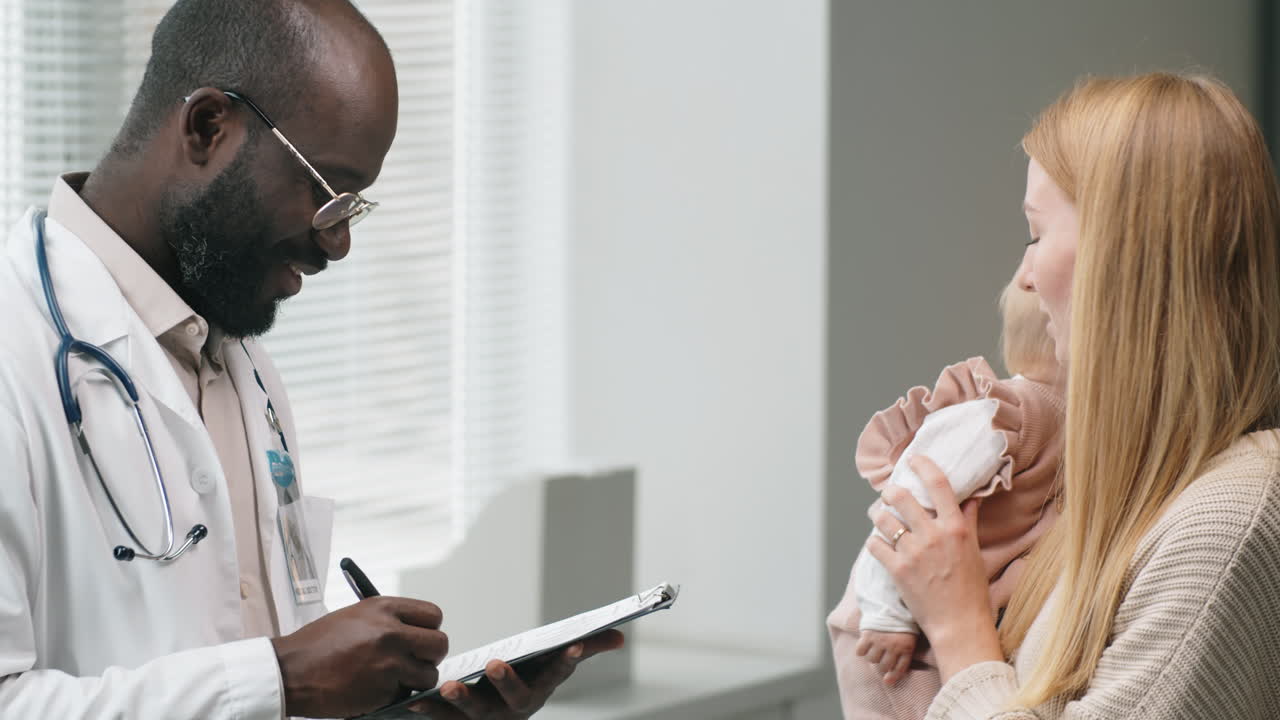 Woman with Baby Having Consultation with Male Doctor in Clinic
