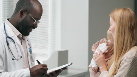 Mujer-Con-Bebé-Consultando-Con-Un-Médico-Masculino-En-La-Clínica