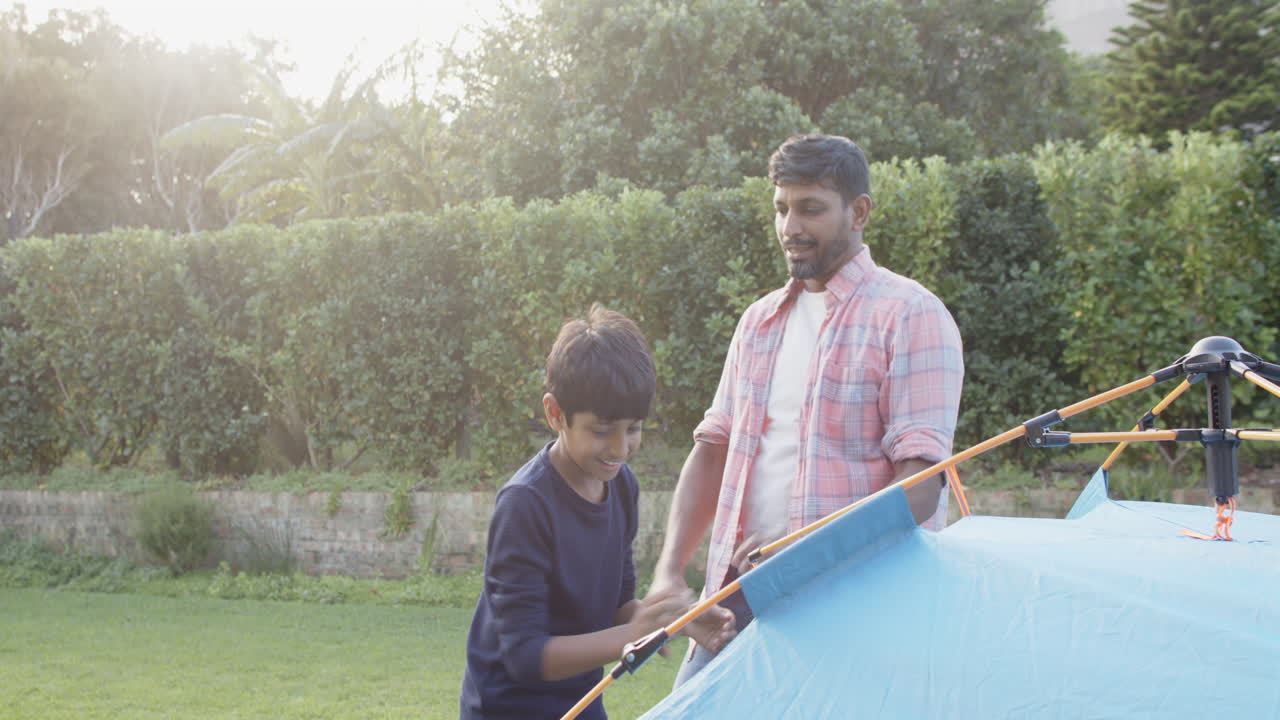 Indian father and son playing together outside near tent, enjoying quality time