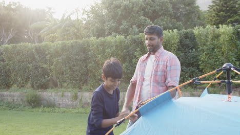 indian father and son playing together outside near tent, enjoying quality time