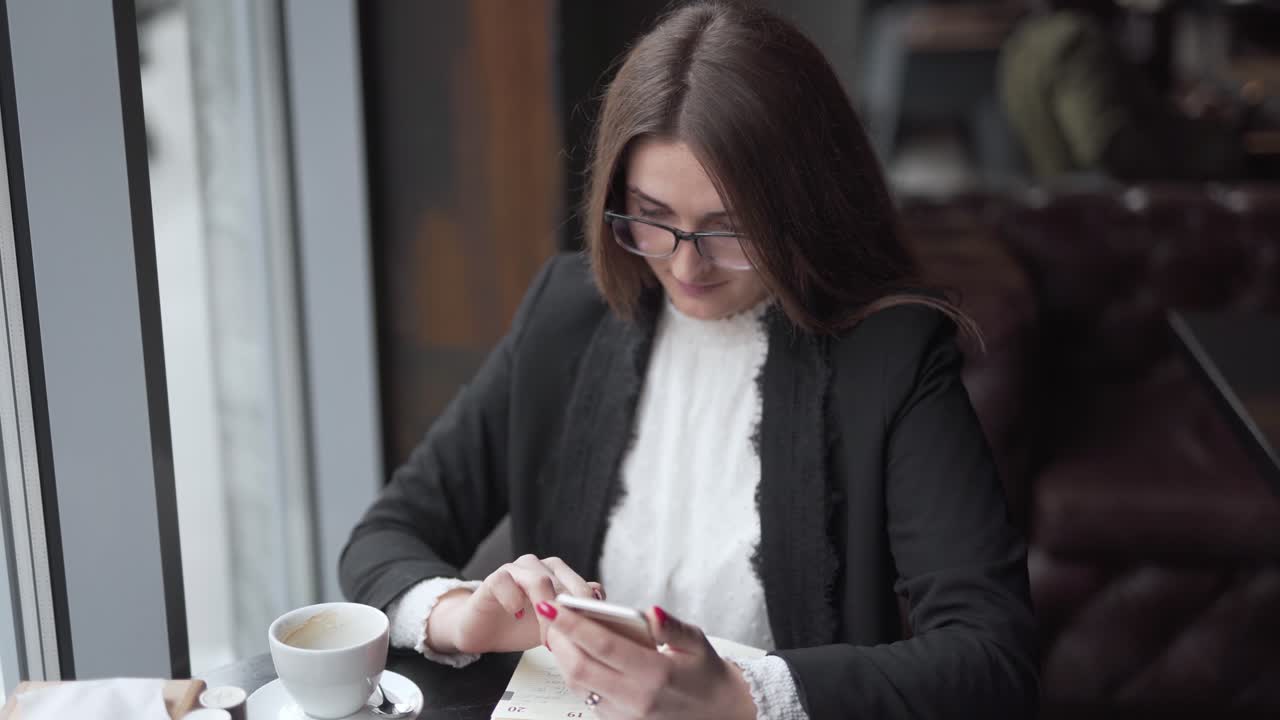 Woman sipping coffee while working from cell phone