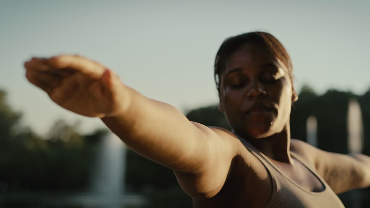 Donna afroamericana che pratica yoga al parco.