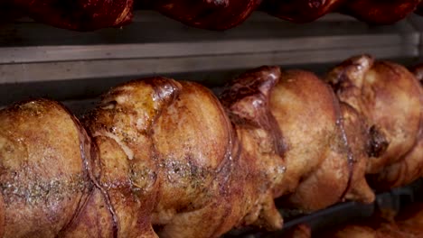Close-up-tilt-down-of-chickens-turning-on-rotisserie