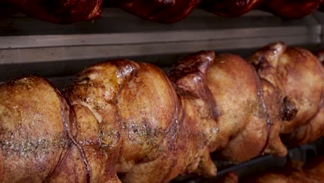 close up tilt down of chickens turning on rotisserie