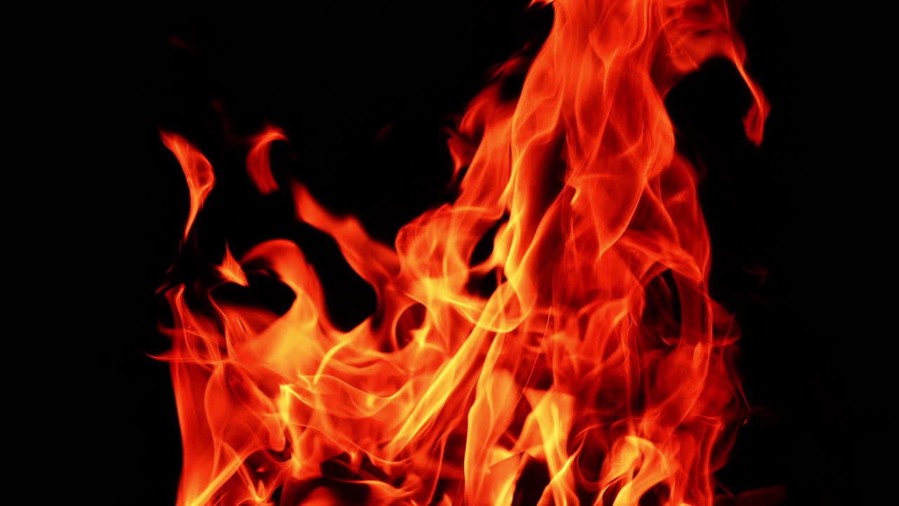 Hot orange flames of a big campfire rising into the air. Beautiful view of the upper part of bonfire close up.