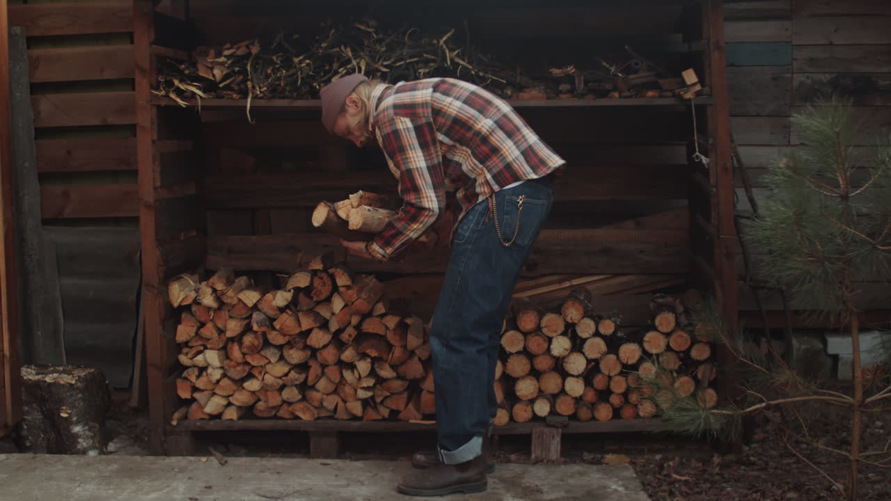 hombre llevando leña de la pila de leña
