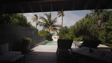 Luxury-exotic-maldivian-apartment-with-private-wooden-terrace,-sunbeds-and-swimming-pool-in-golden-sand-beach-with-green-palm-trees-and-blue-sky