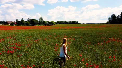 young blonde woman is walking through a poppies field feeling happy