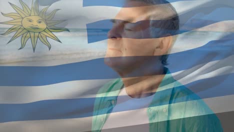 Animation-of-flag-of-uruguay-over-senior-caucasian-man-relaxing-with-eyes-closed-on-beach