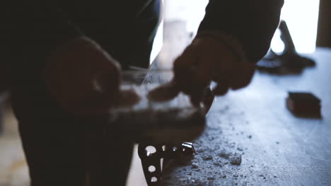 slow-motion cinematic shot of a person scraping wax off of ski after ironing