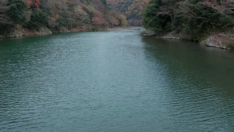 río katsura, inclinación lenta que revela la tranquila escena otoñal de japón.