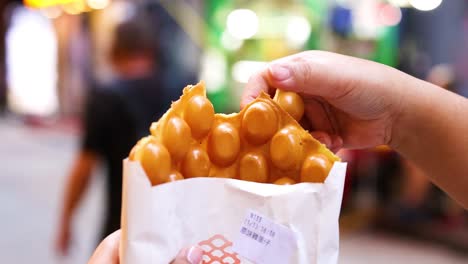 hands holding and eating bubble waffles outdoors
