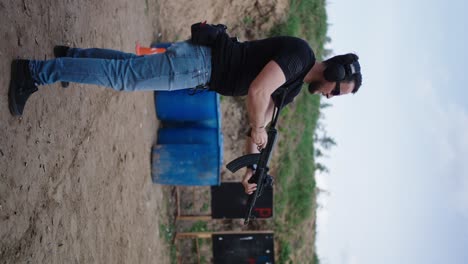 vista vertical de un hombre recargando un rifle de asalto táctico y practicando el tiro al blanco