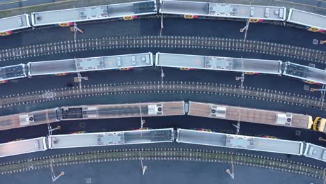 Stationary-top-down-shot-of-train-moving-through-train-yard-with-other-parked-trains-visible