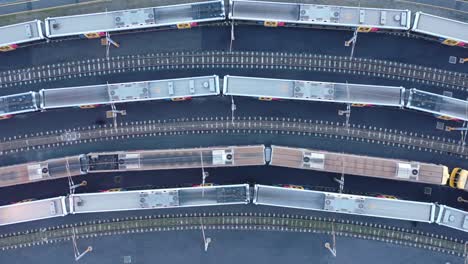 toma estacionaria de arriba hacia abajo del tren moviéndose a través del patio del tren con otros trenes estacionados visibles